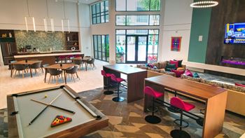 a common room with a pool table and a bar with tables and chairs at Pinnacle Apartments, Jacksonville, FL